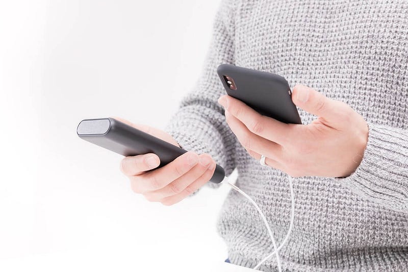 Person holding a phone connected to a mobile battery