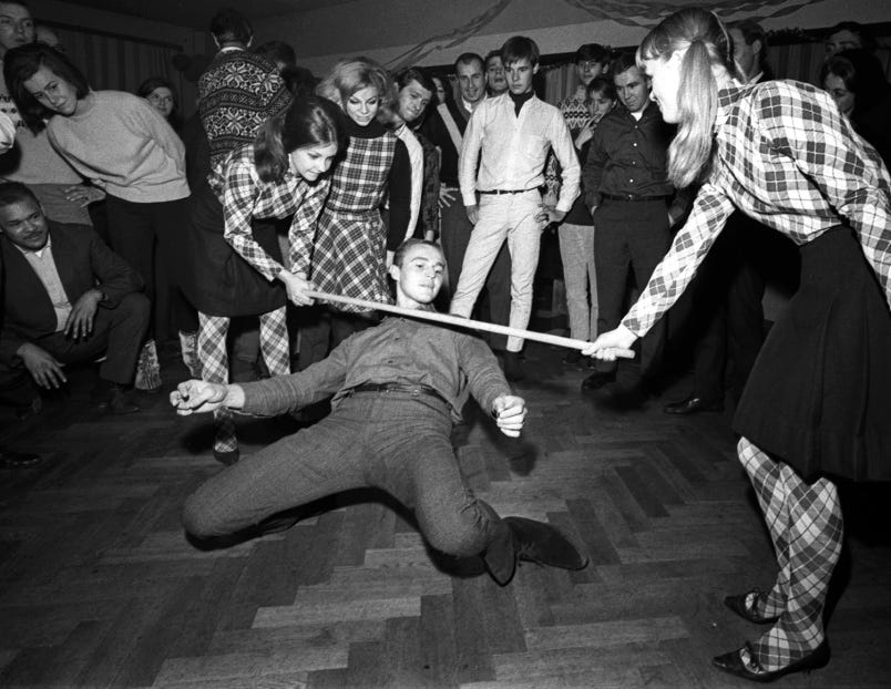 Man doing the limbo with two women holding a low bar.