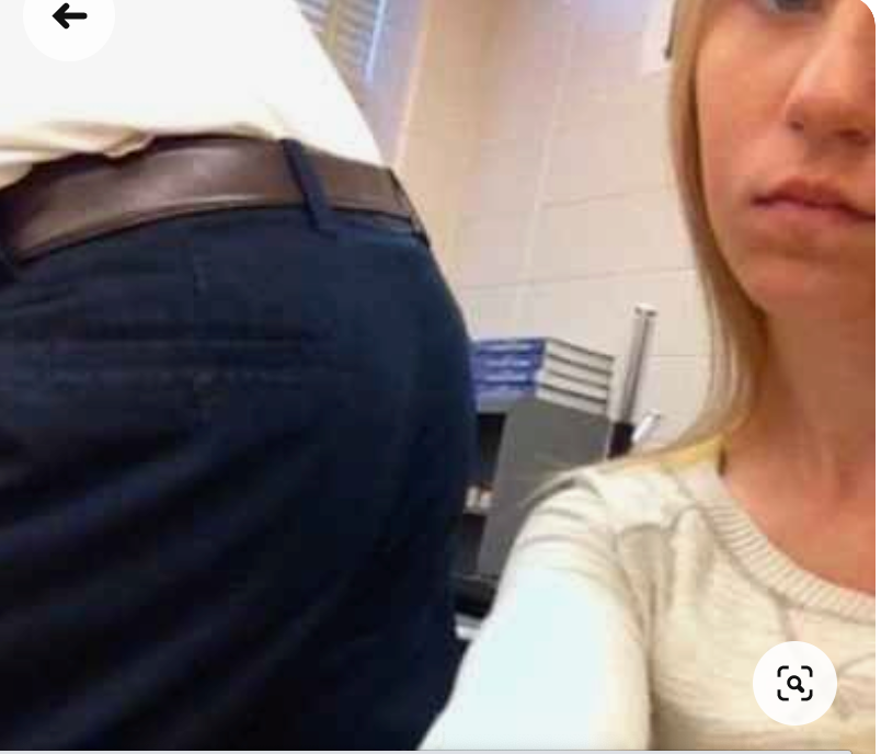 A student looks annoyed that a teachers’ butt is in her face as he leans over to help another student.