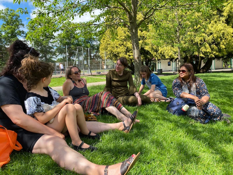 A group of women sitting on grass discussing something