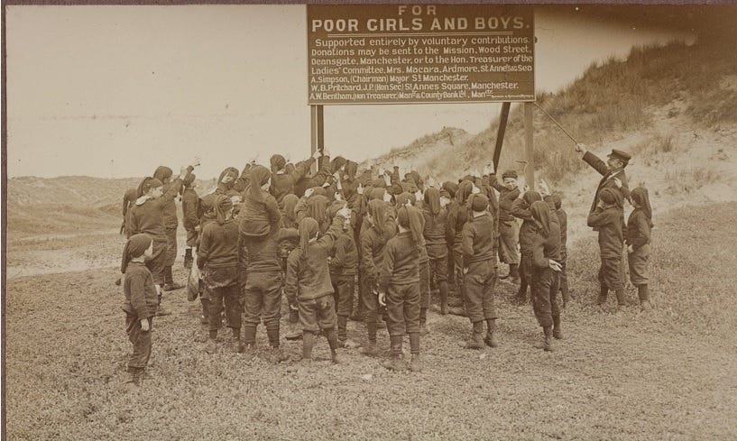 Group of boys on beach holding up a large board that says ‘for poor girls and boys’