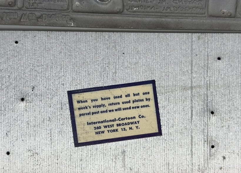 Metal plate with sticker on back that reads “When you have used all but one week’s supply, return used plates by parcel post and we will send new ones. International-Cartoon Co., 260 WEST BROADWAY NEW YORK 13, N. Y.”