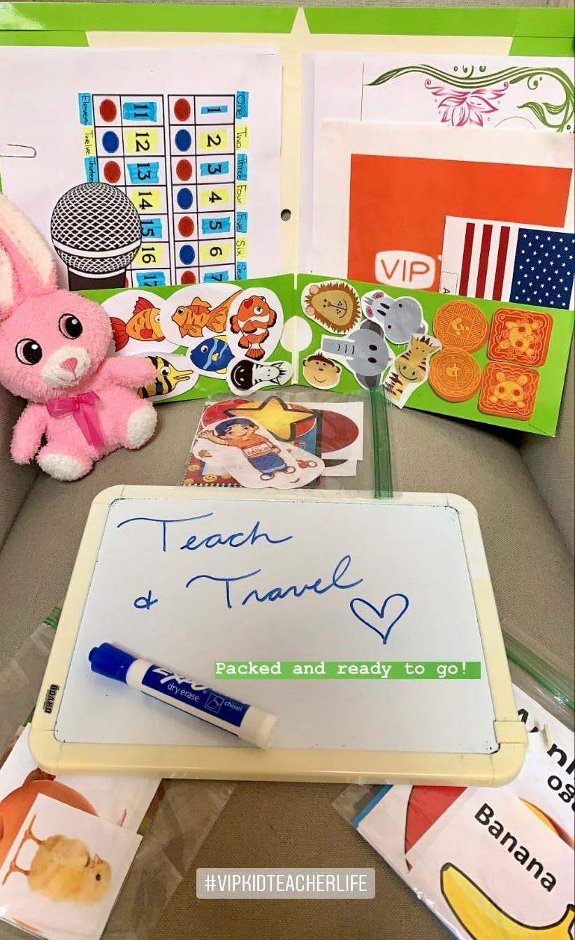 Green folder full of colorful print outs and 2D props. Pink bunny and white board that reads Teach and Travel.