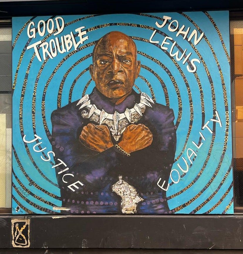 a large mural painting of John Lewis as Black Panther crossing his arms in a “Wakanda Forever” sign. With words that say Justice and Equality
