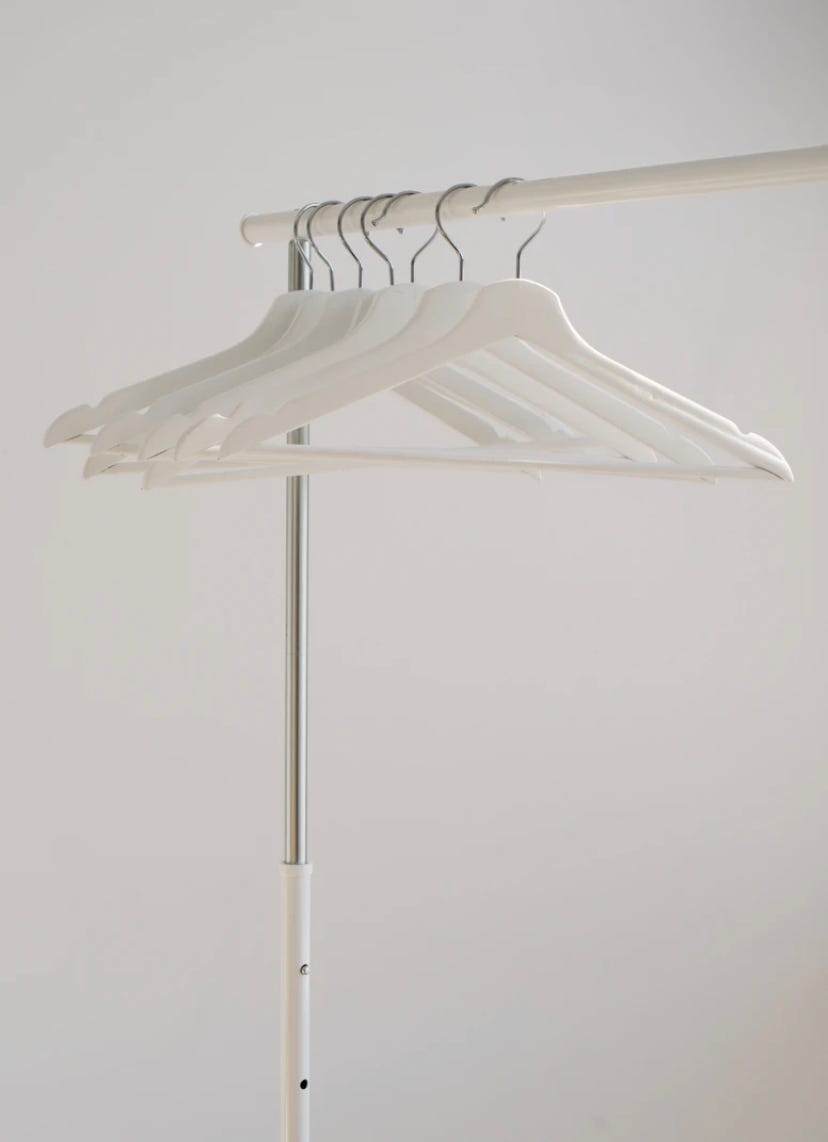 White clothes hangers hanging on rack.