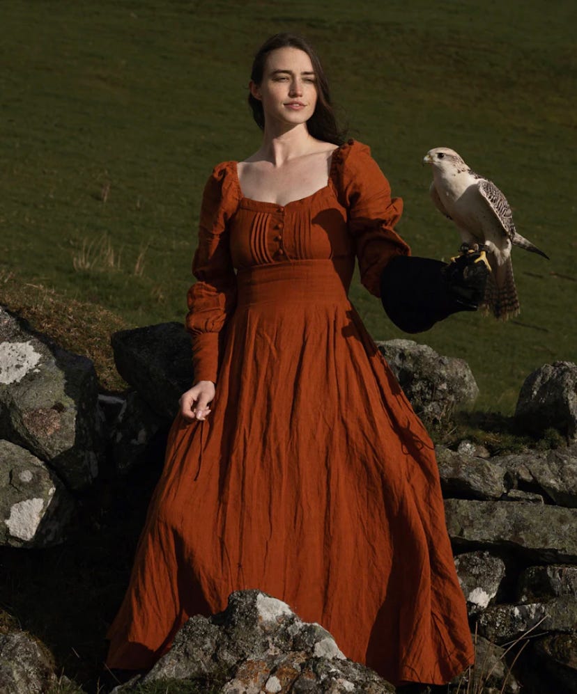 A woman in an orange dress holding a bird.