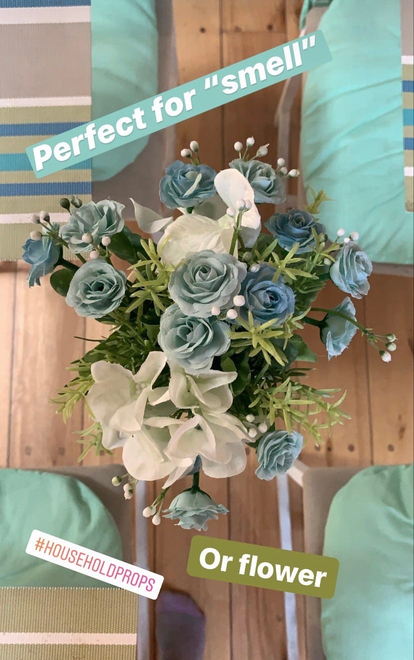 Image of blue, white, and green fake flowers on a table. An example of realia; a tool in the TEFL classroom.