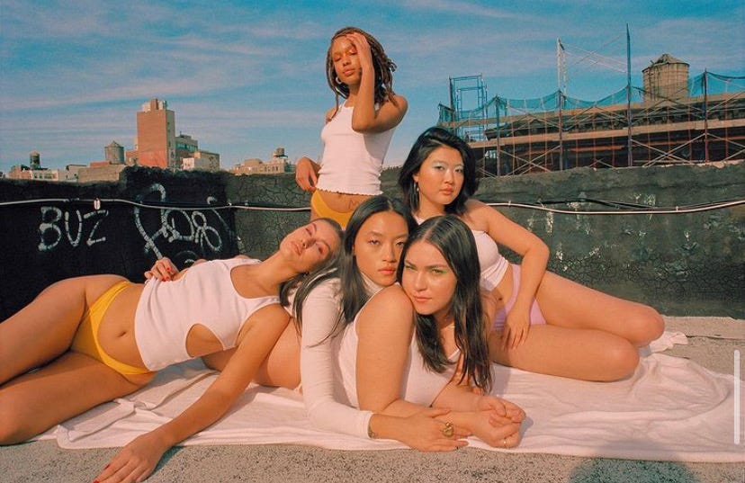 Group of five women posing together on a city rooftop in white tops and Siren Basics underwear