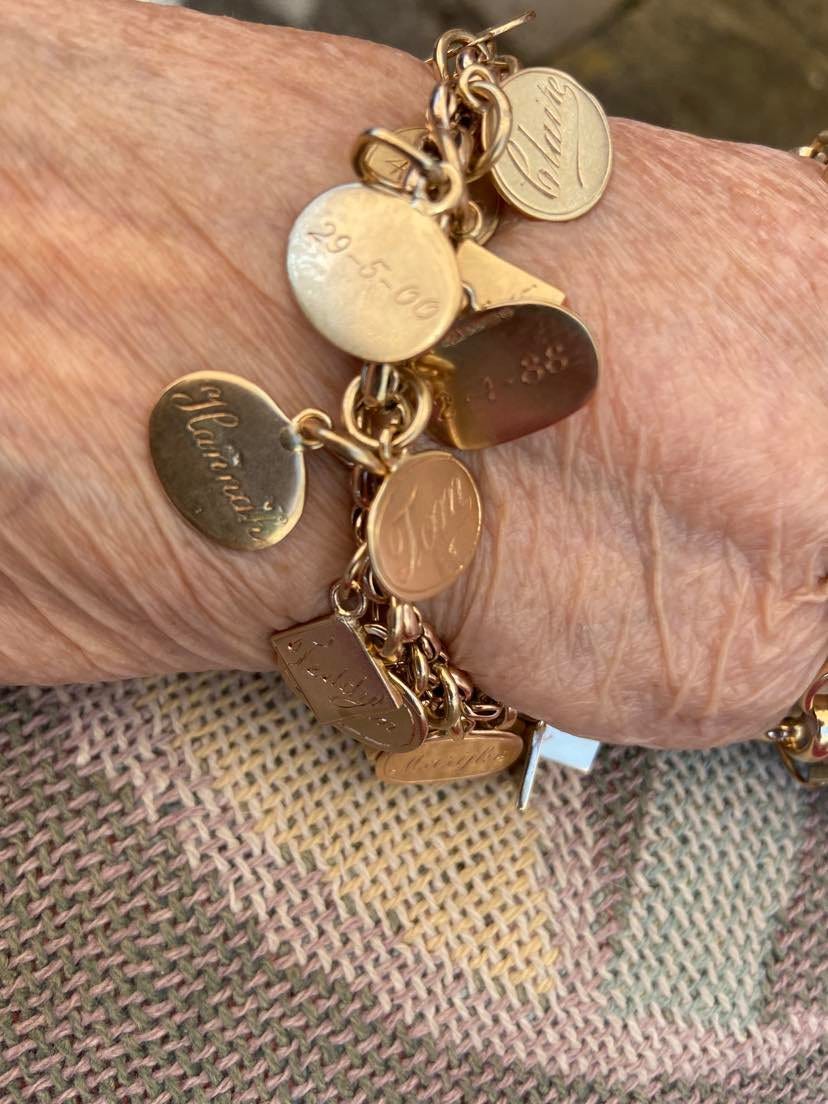a gold braclet with lots of small gold medallians attached. Each medallian has the name of a daughter, grandchild or great grandchild on it with their date of birth