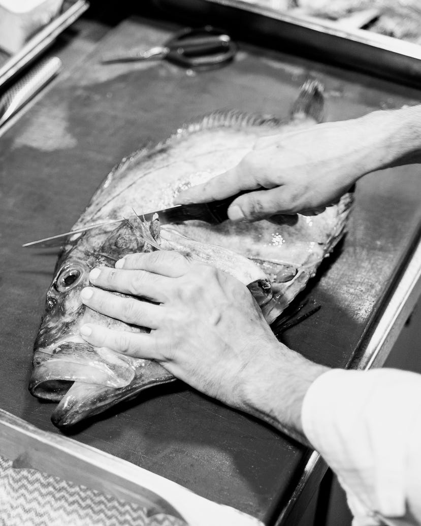 Fresh fish being filleted in London fine dining restaurant kitchen for dish preparation. Food ingredients by Food Story Media