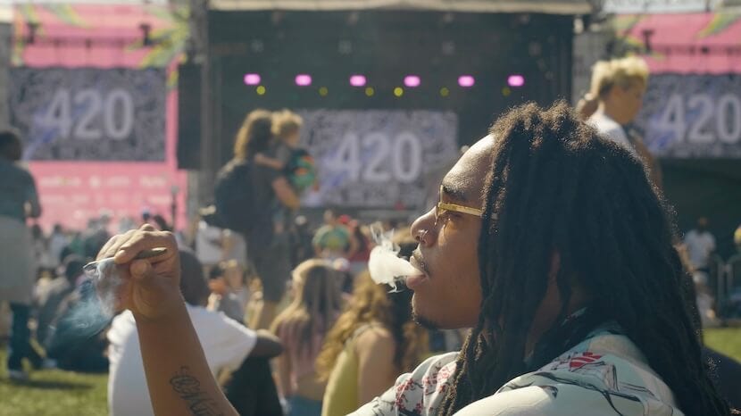 A man with dreads, sitting on the grass and smoking a blunt, at the Mile High 420 Festival in Denver, Colorado. Image via Mile High 420 Festival.