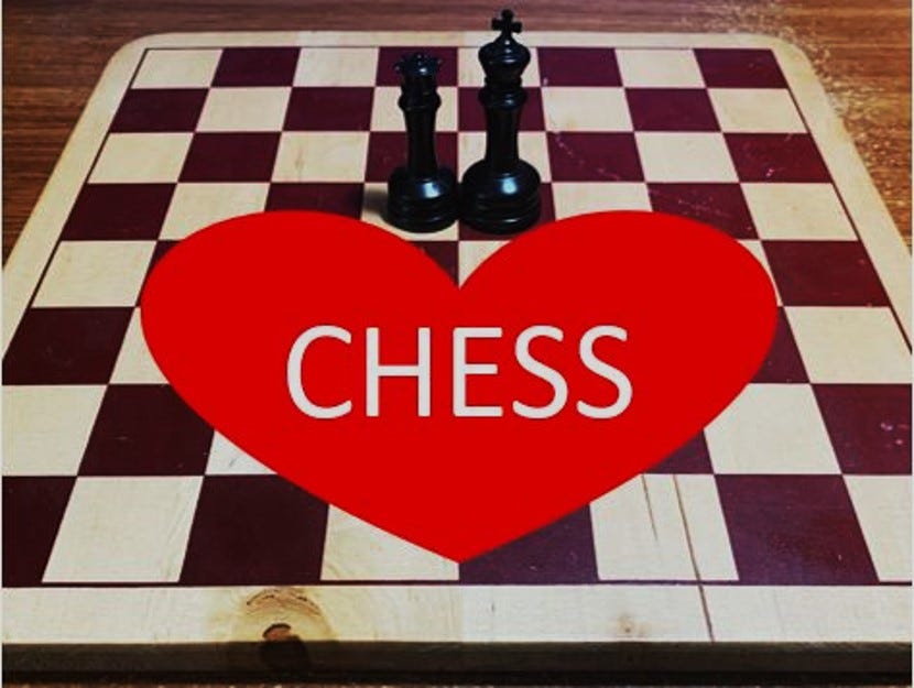 Black king and queen in center of author’s well-used wooden chess board. Red heart in center with the word CHESS.