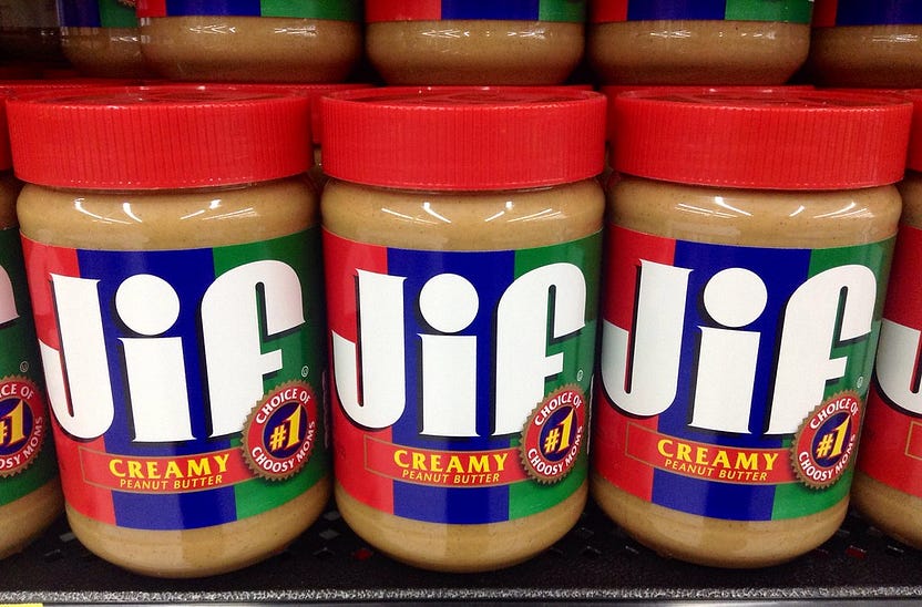Several Jif Peanut Butter containers on a store shelf