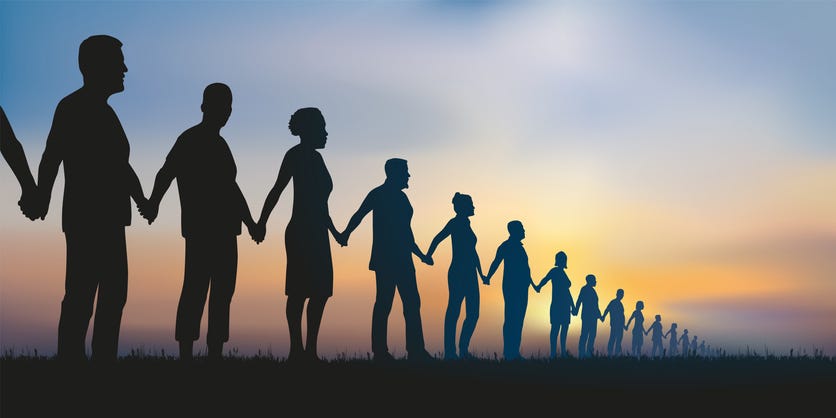 Silhouettes of people holding hands across a field.