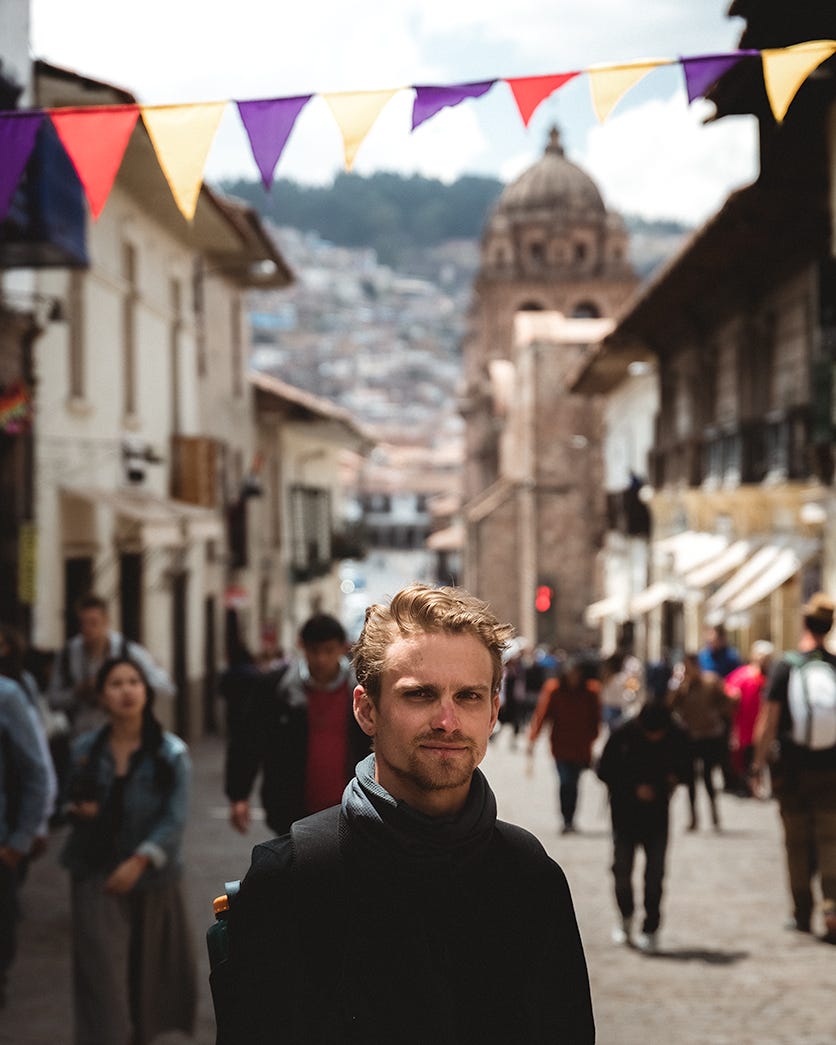 Young man standing on a Peruvian street staring at you.