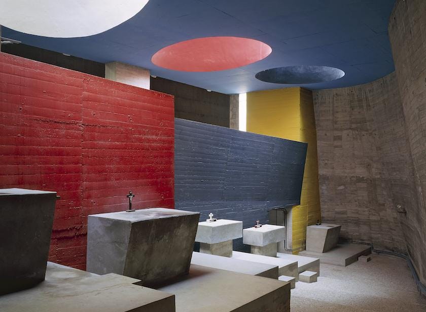 Large circular light shafts painted in cherry red and deep grey relate to the color-blocked walls in the crypt of La Tourette