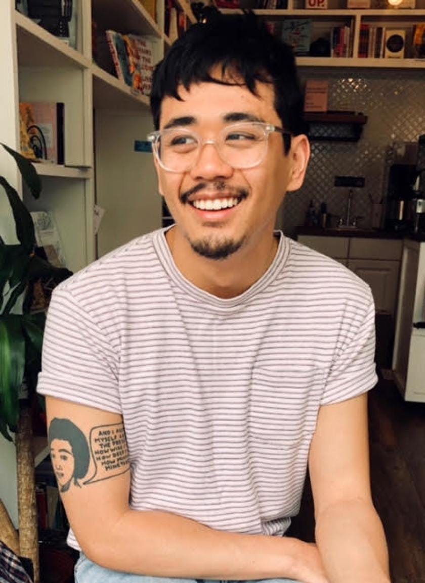 Author Anthony Veasna So, who died last year at age 28, was a rising literary star, smiling broadly, with clear plastic glass frames and a t-shirt with red stripes, with a tattoo of a woman and a text bubble on his right arm (photo by Alex Torres in the LA Times)