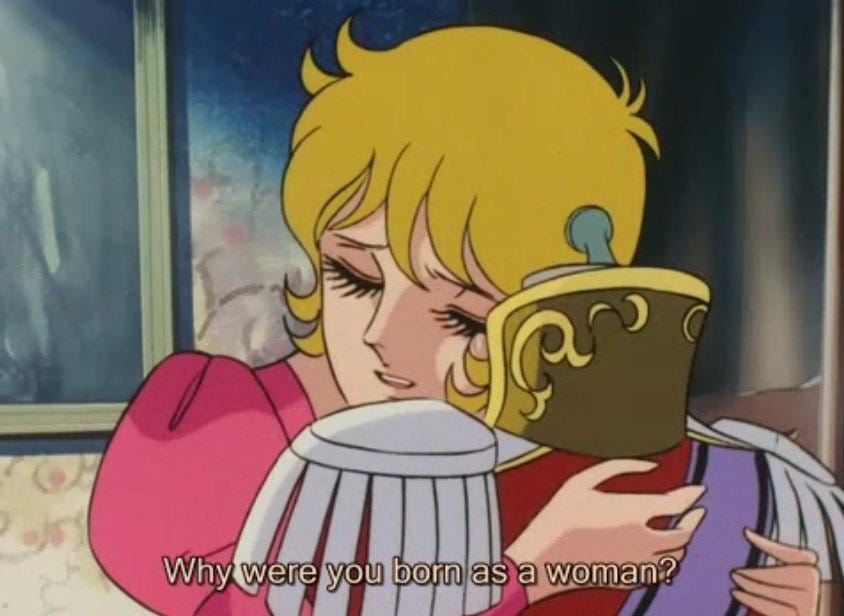 Rosalie in the anime adaptation of Ikeda’s manga, hugging a mannequin with Lady Oscar’s uniform on it. Subtitles say, “Why were you born as a woman?”