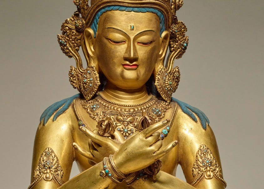 A golden figure of a Buddha, with a large golden crown, hands crossed on its chest.