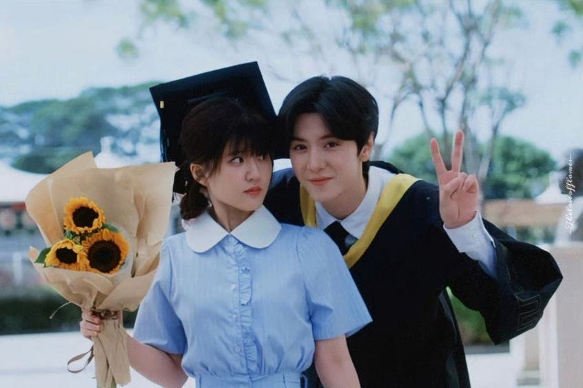 Sang Zhi holding a sunflower bouquet looking at Duan Jiaxu holding up a peace sign to click a photo together at his Graduation ceremony