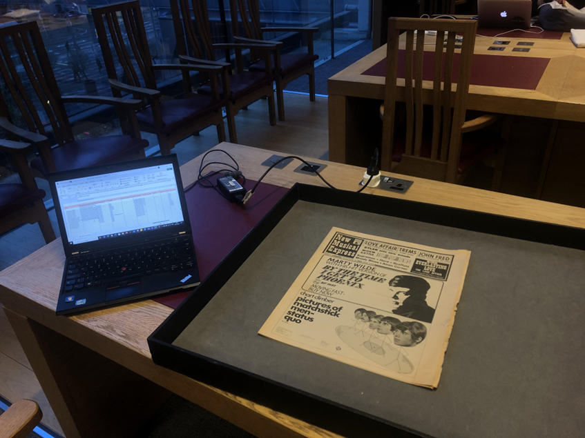 Table with laptop and an archival item in a tray