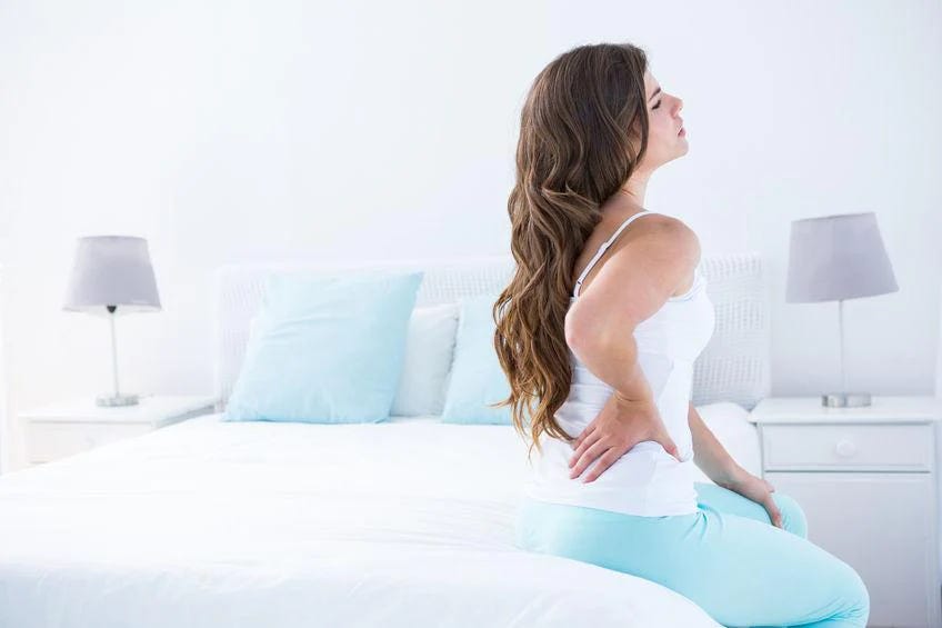 Woman with scoliosis pain on edge of bed