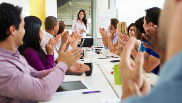 Businesswoman Addressing Meeting Around Boardroom Table