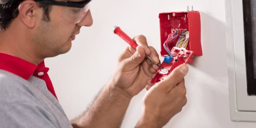 A technician installs a fire detection alarm panel.