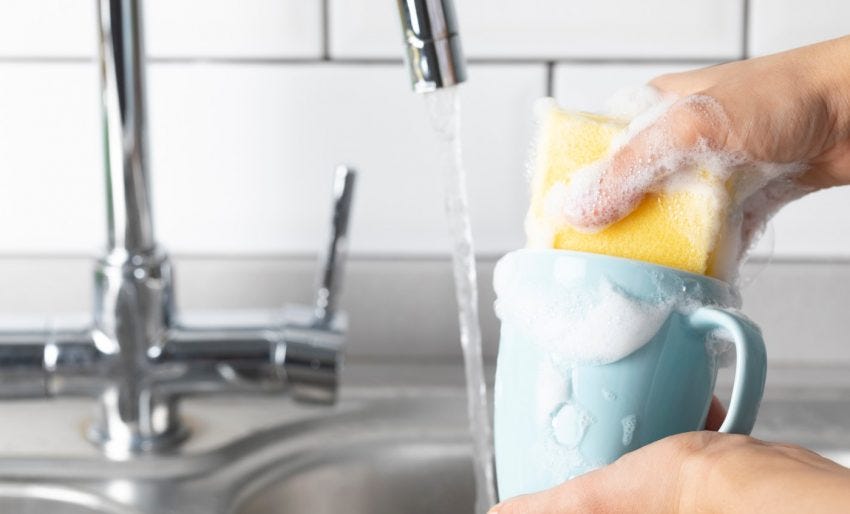 lavando uma caneca azul na pia com esponja