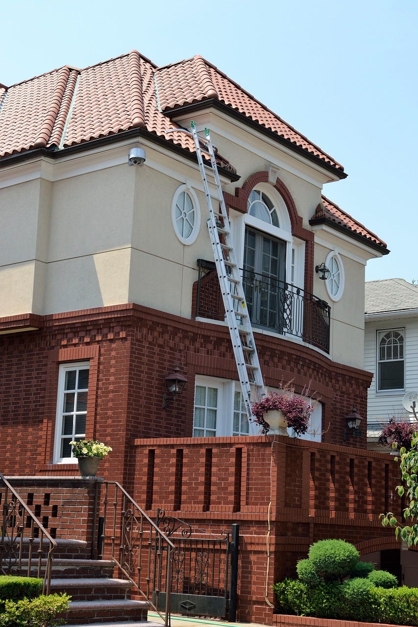 a house with a ladder with roofing work being done