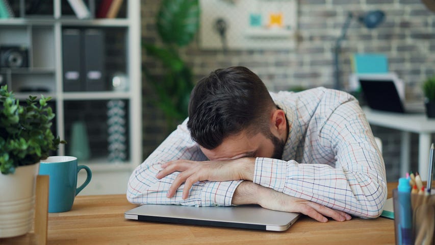 Man at a desk with his head down on his laptop