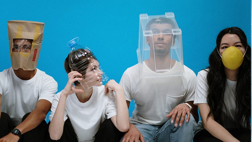 4 people wearing plastic bottles or paper bag on their heads