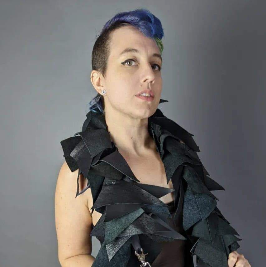 A white woman with a blue mohawk models a leather boa.