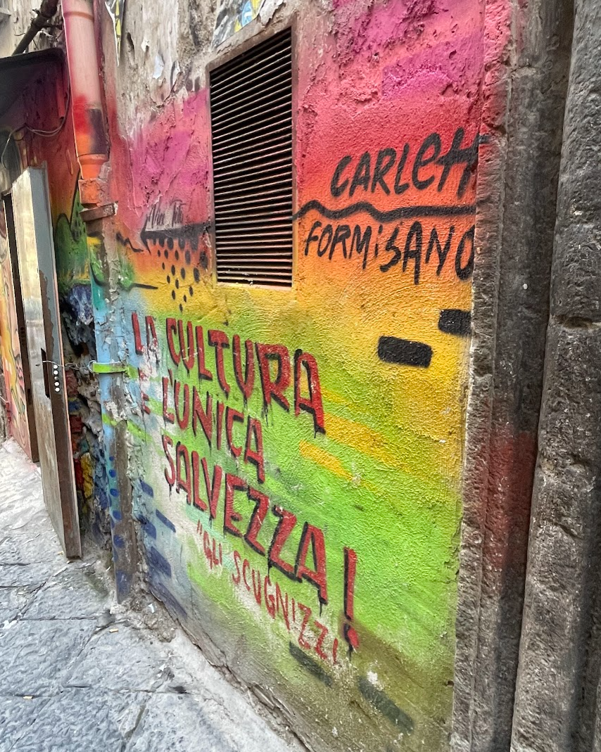 A wall covered in colorful graffiti that says “la cultura e l’unica salvezza”.