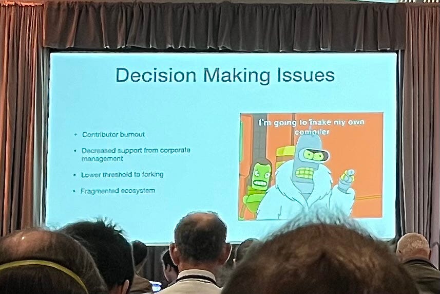 A photograph of a slide from the LLVM governance discussion, highlighted by Bender from Futurama declaring he’s going to go build his own compiler.