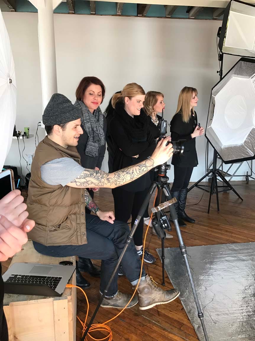 Young man photographing in studio, with crew by his side