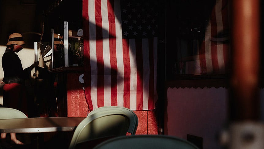 American flag inside diner, with woman at register in background