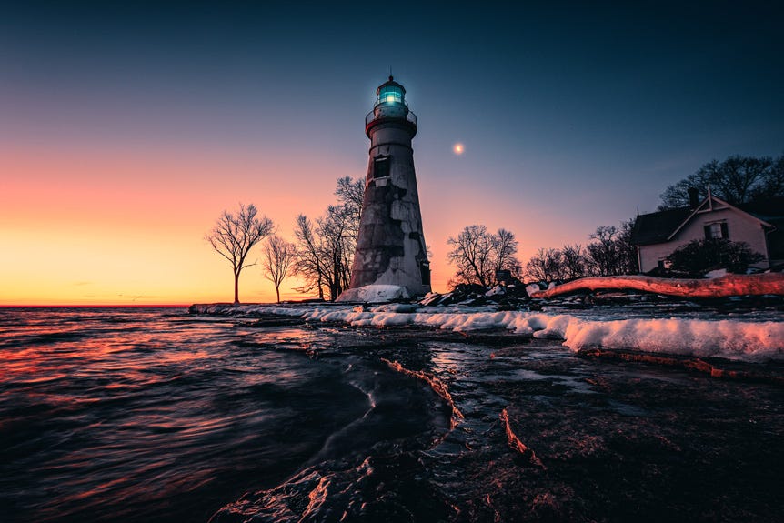 Lighthouse on icy shore at dusk