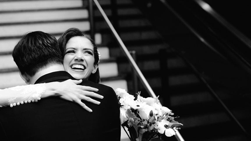 Happy bride hugging groom on stairs