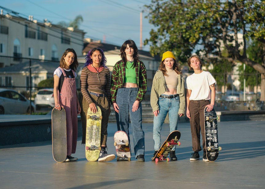 Group of young woman skateboarders standing in skatepark