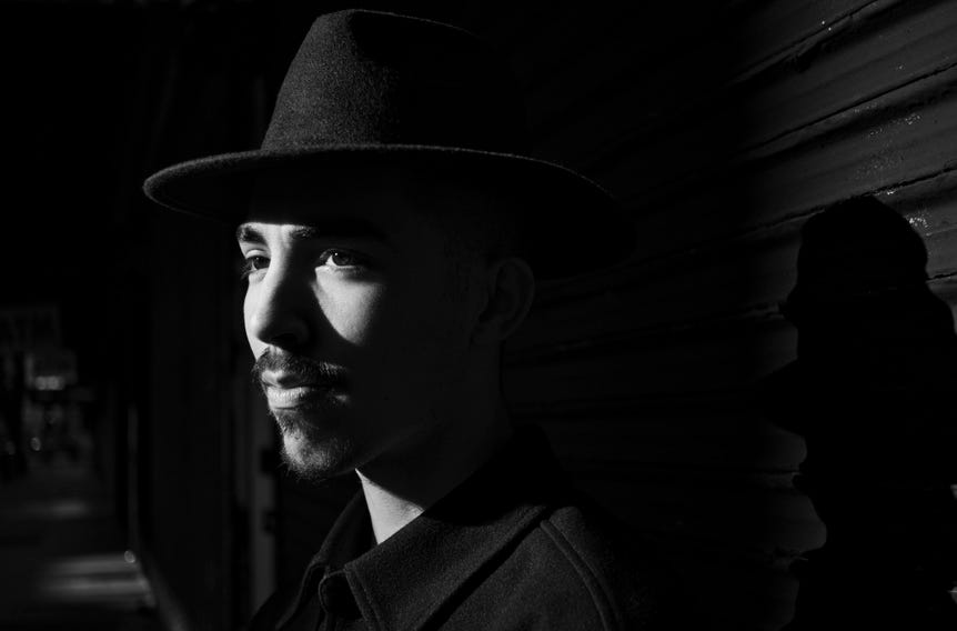 Monochrome portrait of a young man with a goatee and fedora hat