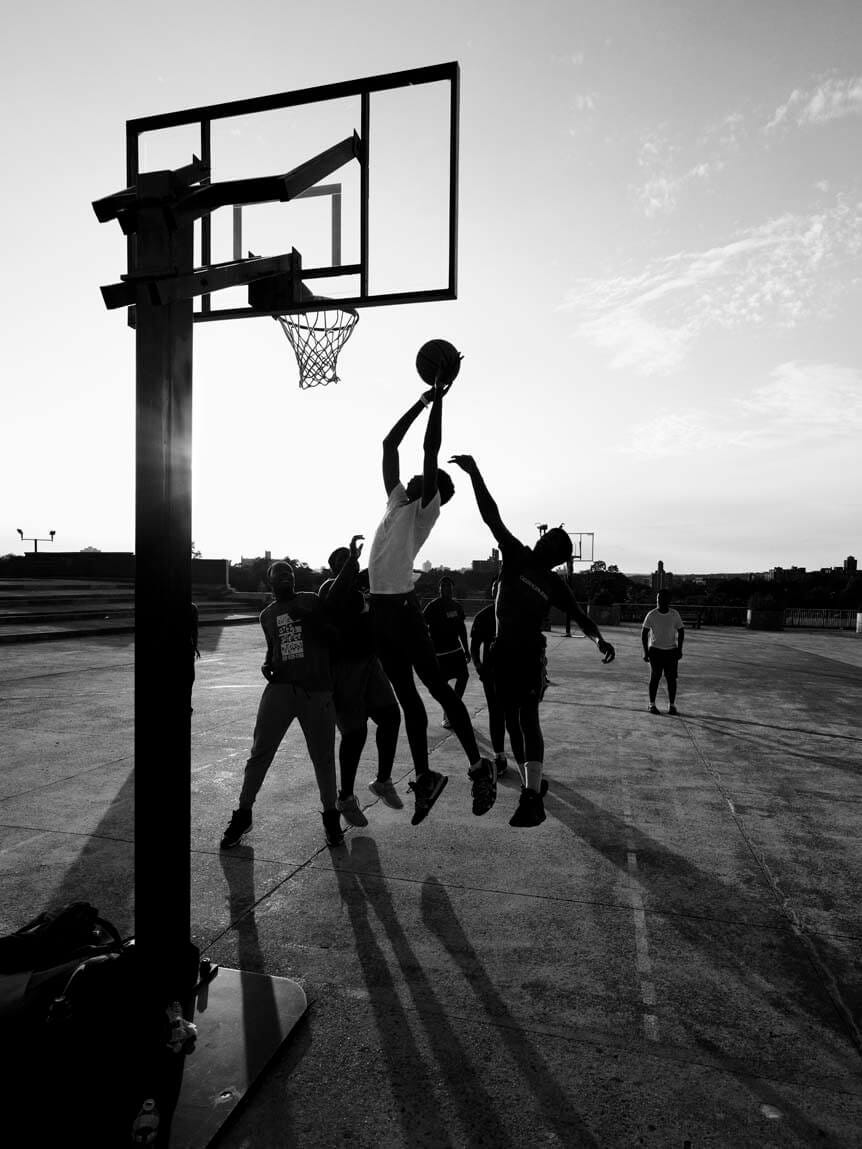 Young men playing basketball in bright sunlight