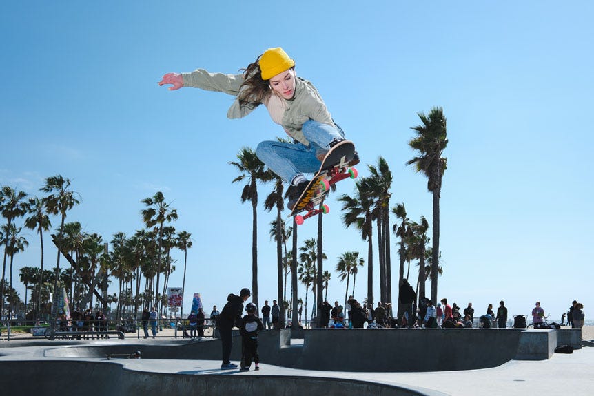 Young woman flying out of skatepark bowl on skateboard