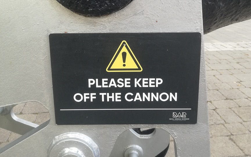 Close up of a warning sign that reads ‘Please keep off the cannon’ with a small logo reading ‘Royal Arsenal Riverside’. Taken in Woolwich, part of the Royal Borough of Greenwich.