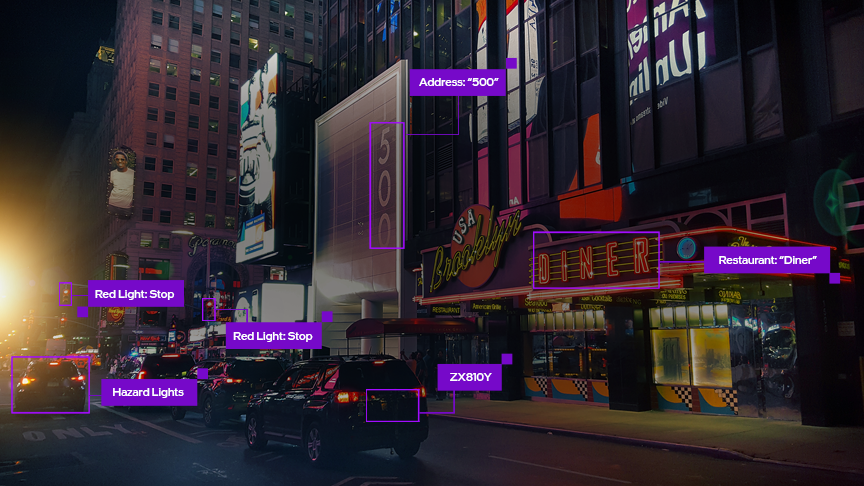 Image of AI computer vision in action identifying and classifying buildings, signage, a vehicle license plate, and traffic signals.