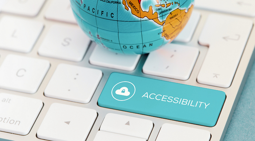 a small metal toy globe sits on a computer keyboard. one of the keys is labeled “accessibility.”