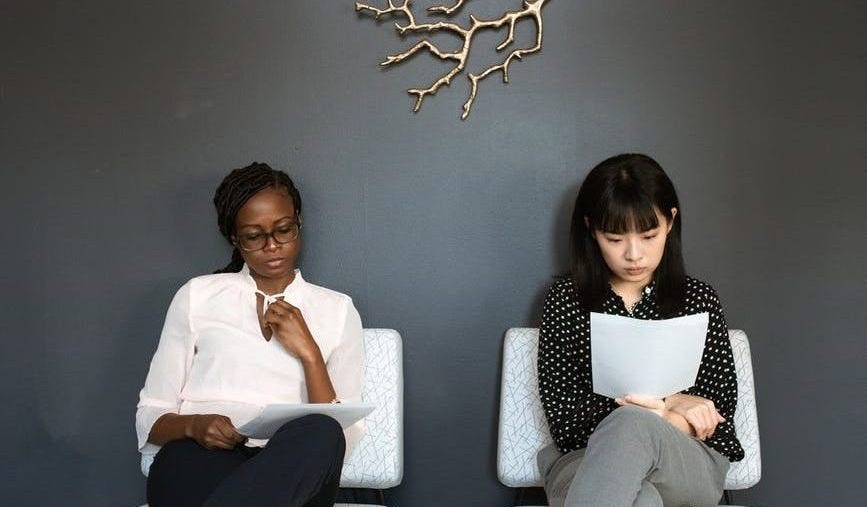 2 people looking at sheets of paper which look like a CV.