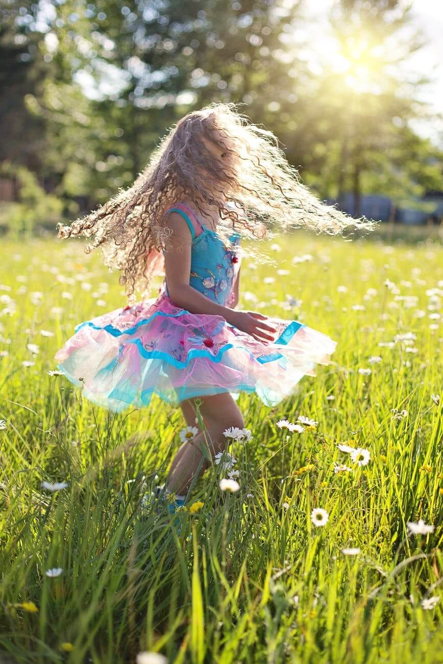 Girl in frock swirling in a flowery field