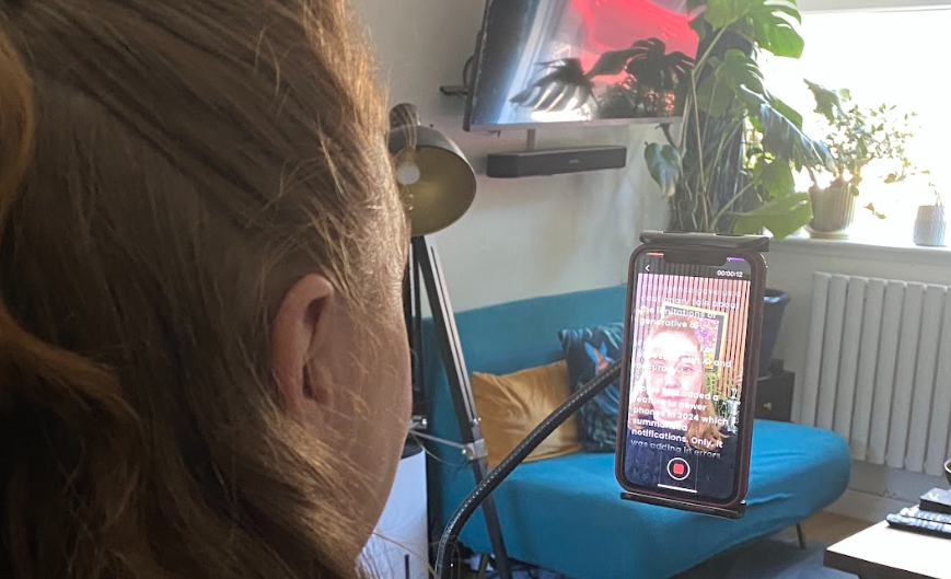 Clare Spencer reads an autocue from the Sophina app on her phone screen.