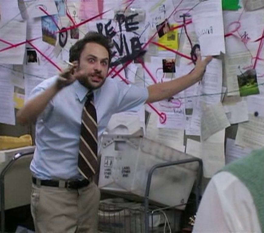 A man in a shirt and tie pointing urgently at a wall covered in papers, photos, and red strings, referencing the “conspiracy theory” meme format.